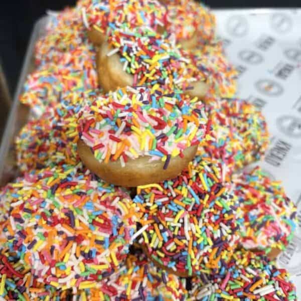 Colorful donuts with rainbow sprinkles stacked high for Tamariki Mini.
