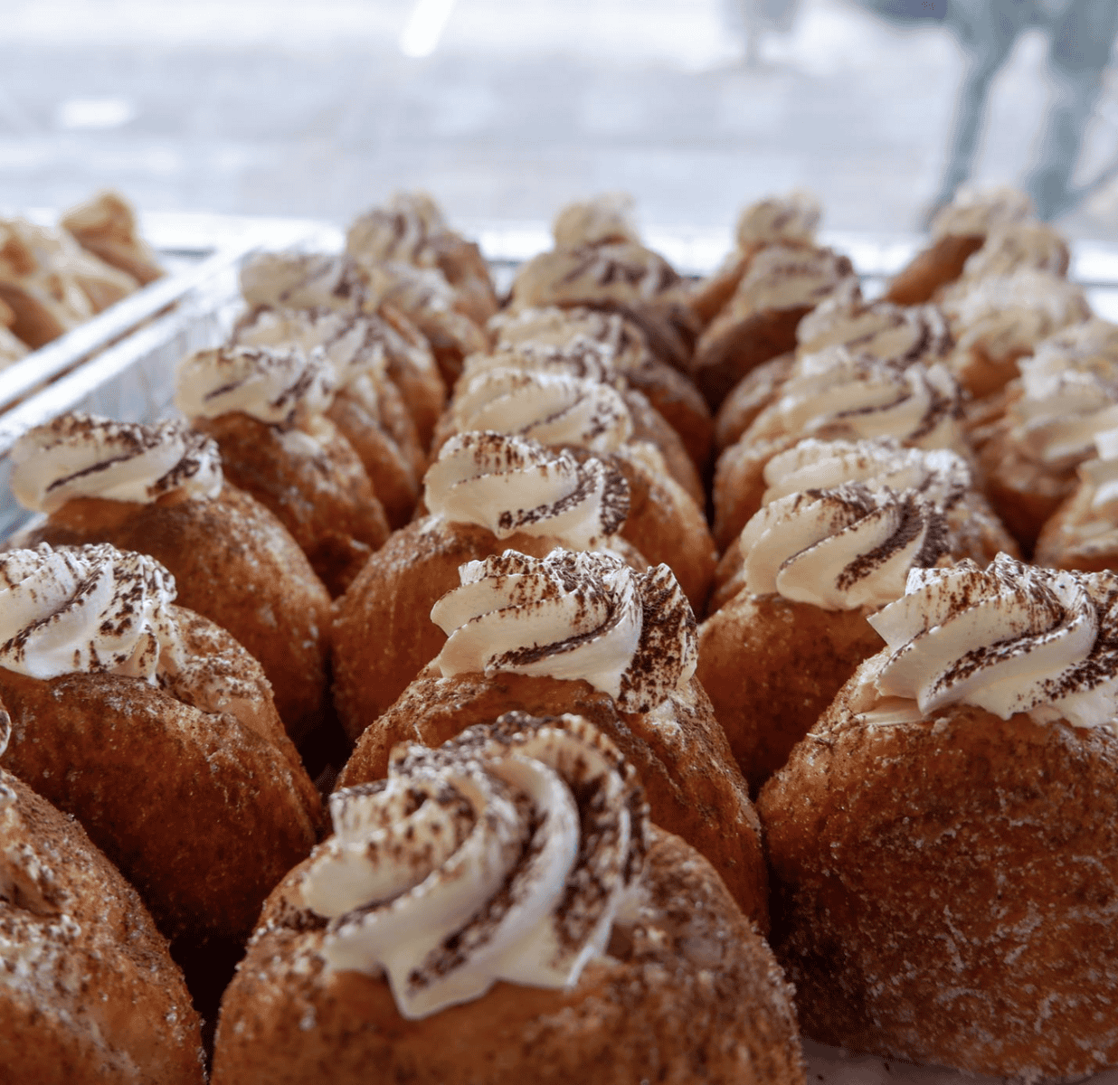 Close-up of freshly baked doughnuts topped with creamy frosting and sprinkled with cocoa powder, perfect for a sweet treat.