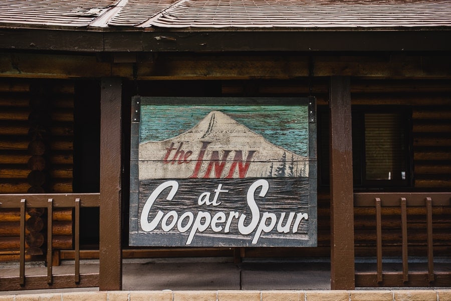 A sign for The Inn at Cooper Spur showcases a mountain illustration against a rustic wooden lodge background.