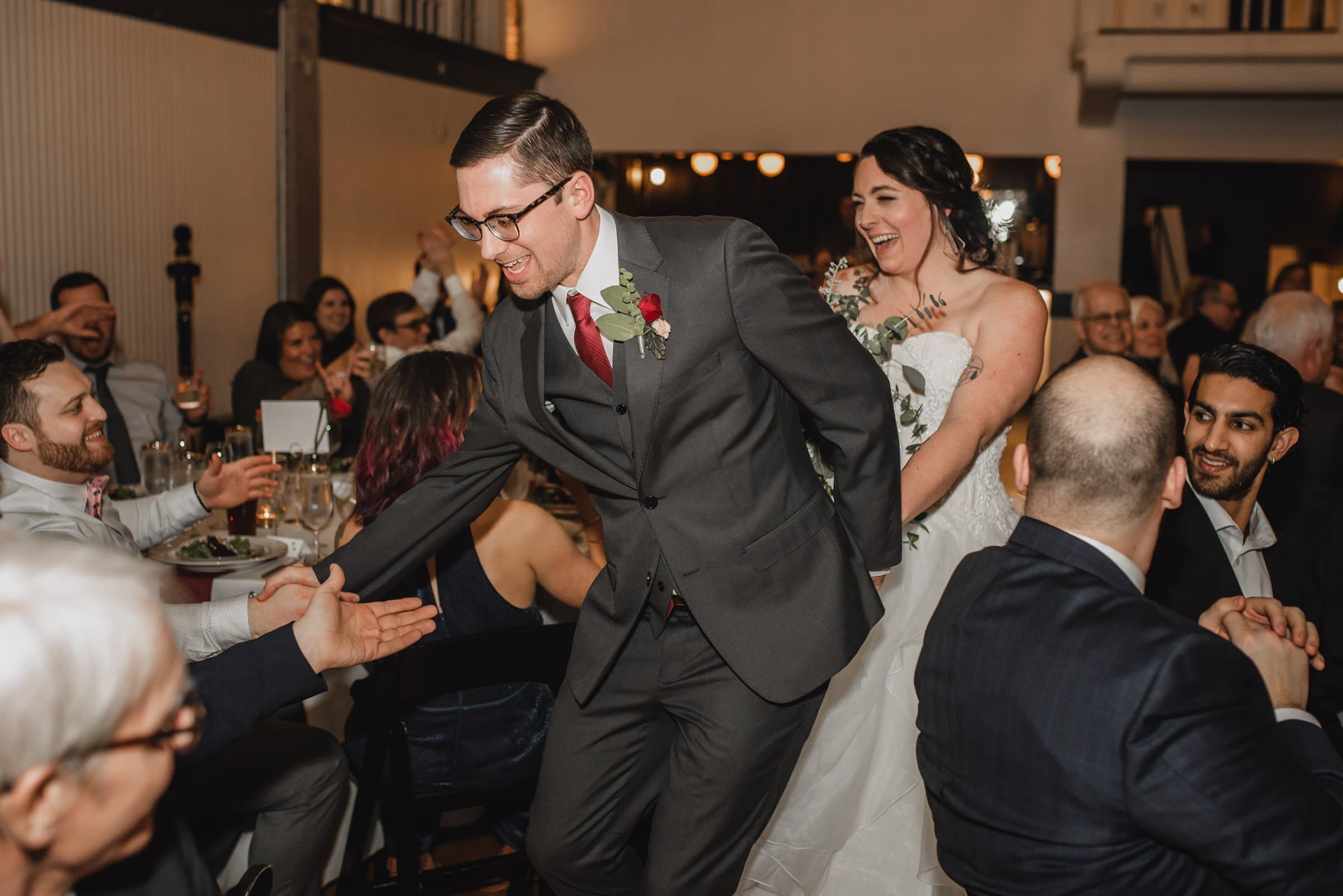 The bride and groom joyfully greet guests as they walk through the wedding reception, creating perfect moments for memorable wedding photos at The Evergreen.