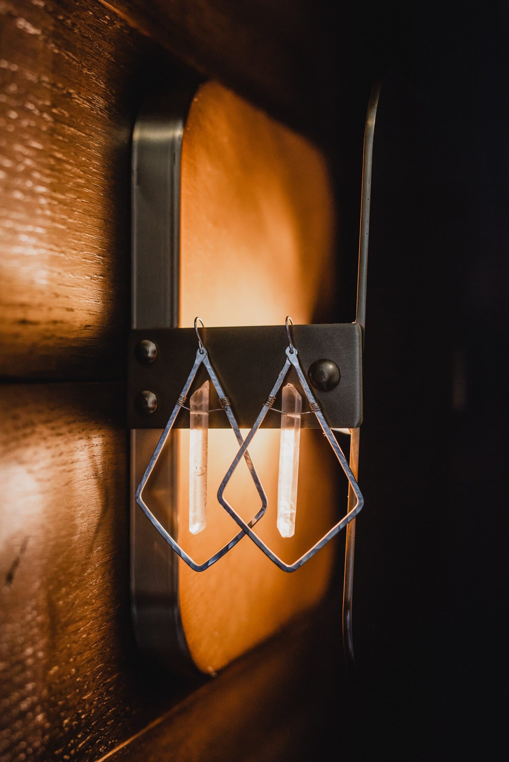 Diamond-shaped earrings hanging on a metal wall sconce with a warm light glow, setting the perfect ambiance for getting ready at the Hi-Lo Hotel.
