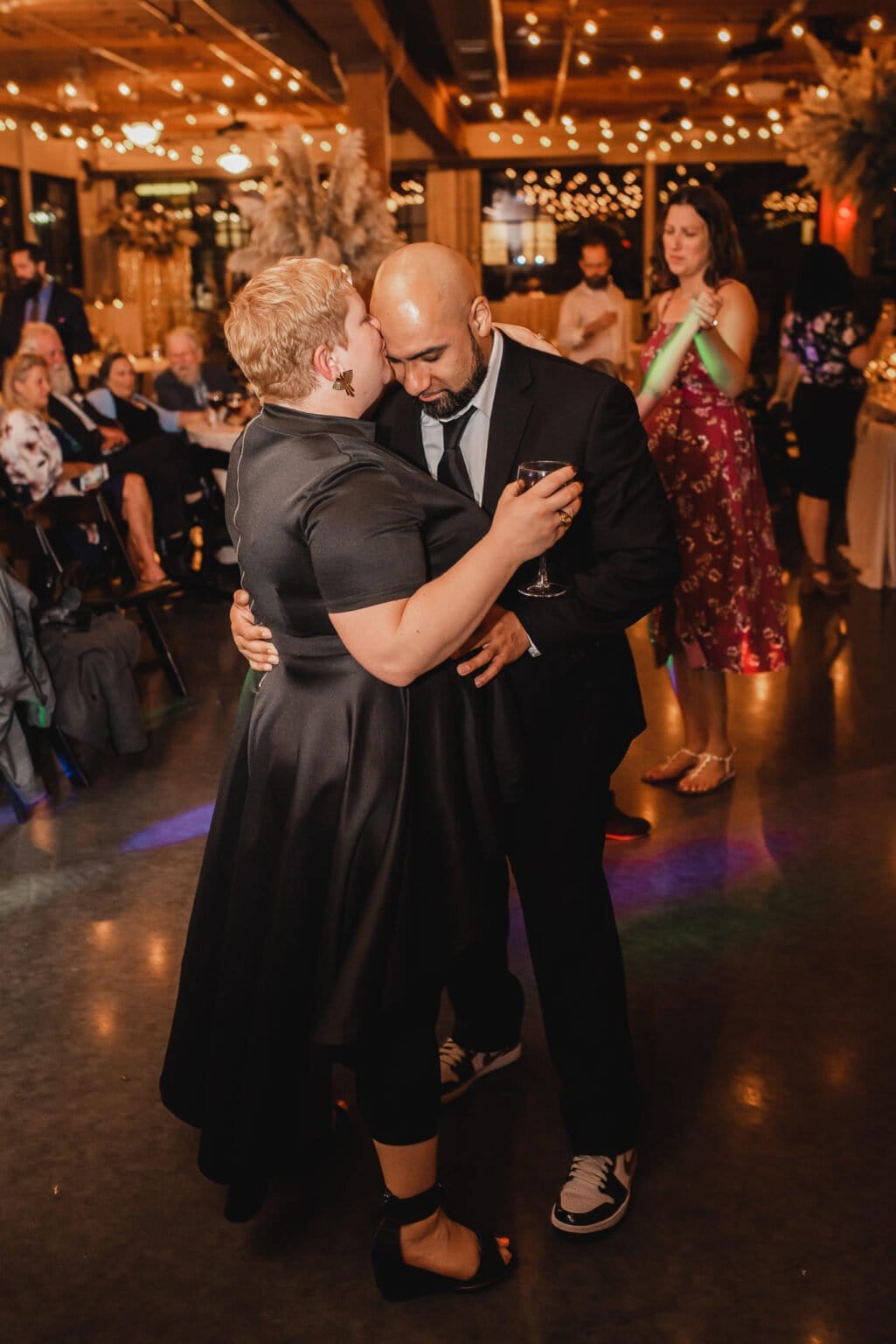 A couple in formal attire shares a slow dance at a festive gathering, captured beautifully as part of wedding photos at Castaway Portland.