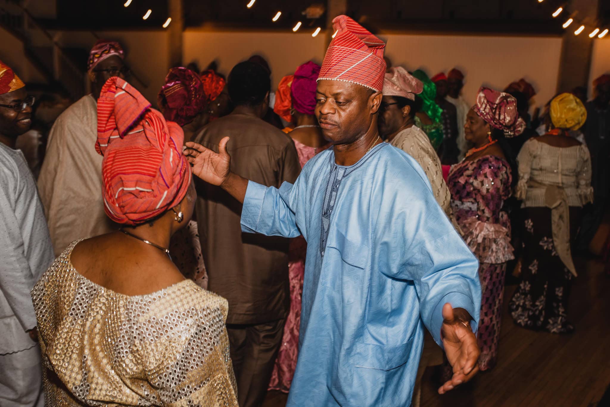 People in colorful traditional attire dancing energetically at a lively wedding celebration at the Evergreen.