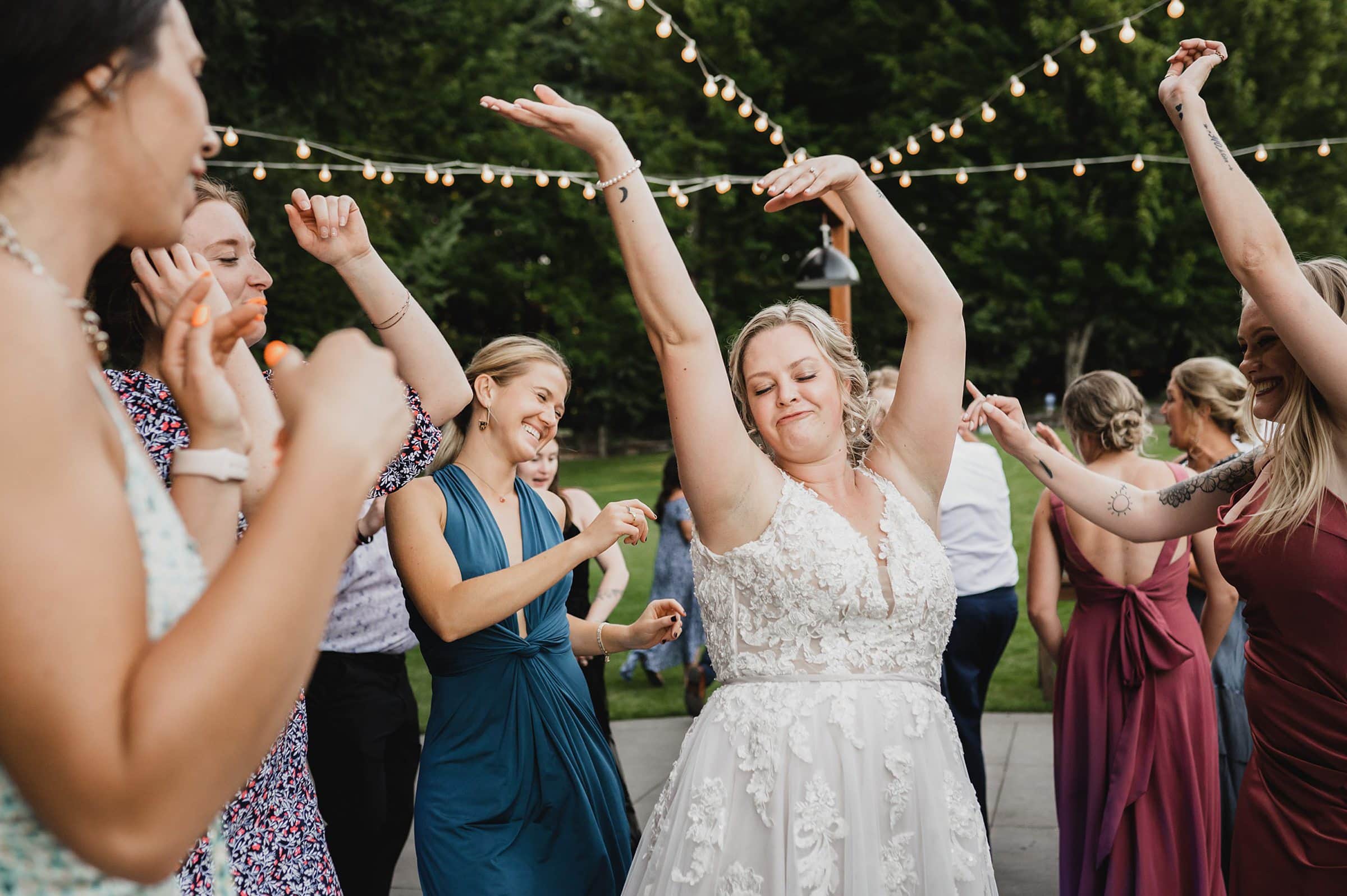 The bride danced joyfully with guests under the string lights, creating beautiful memories at the Gorge Crest Vineyard wedding.