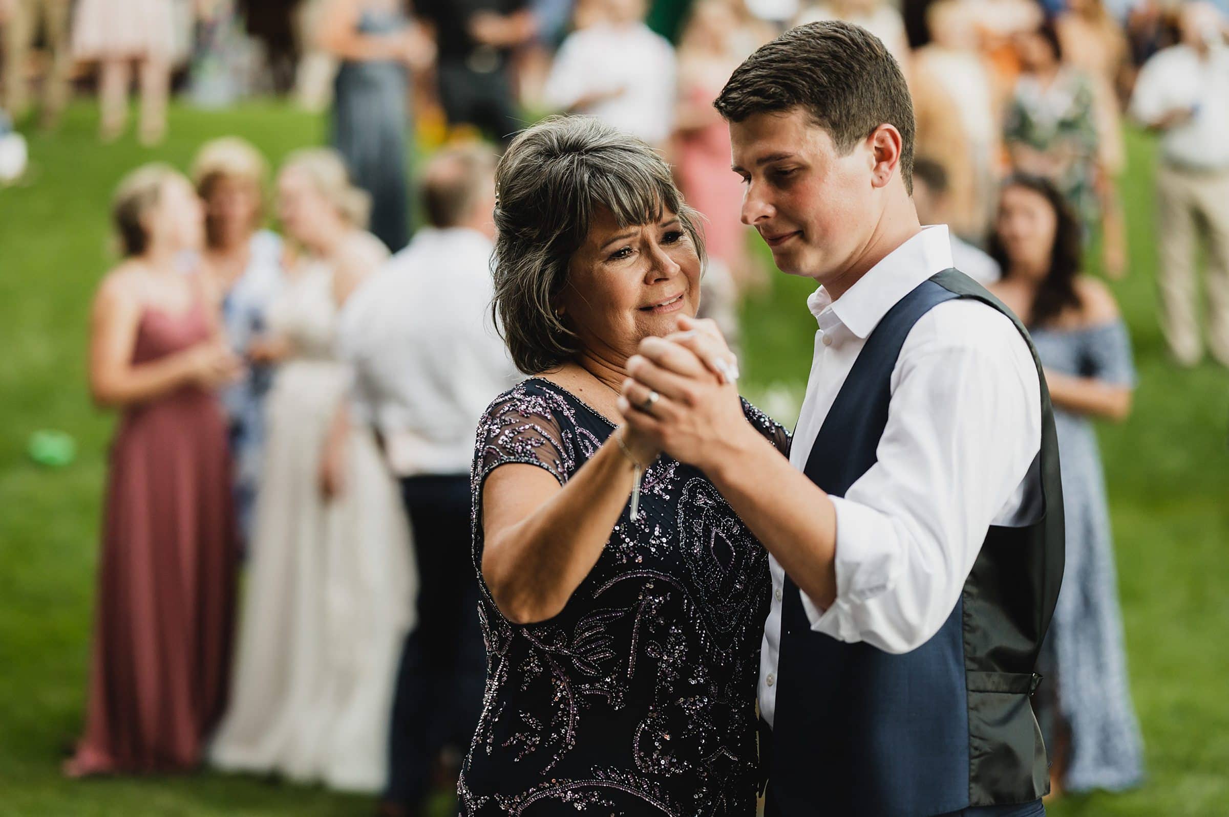 A woman and a man dance together at an outdoor event with a lively crowd in the background, capturing the joyful spirit of Gorge Crest Vineyards wedding photos.