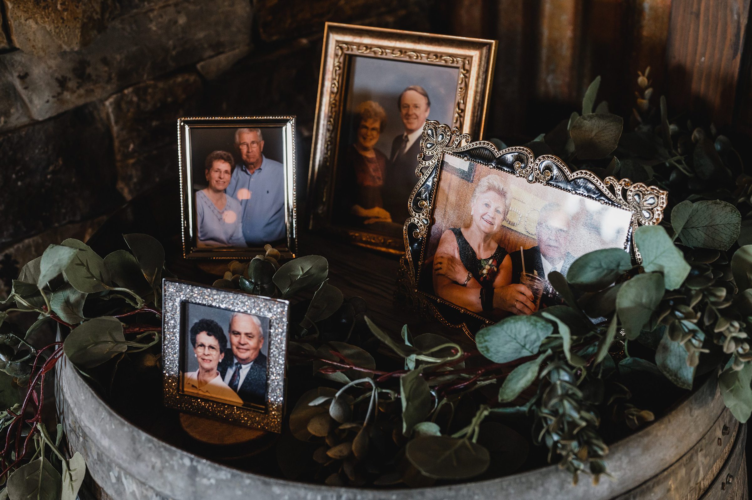 Framed photos of four elderly couples on a wooden barrel, surrounded by greenery at Gorge Crest Vineyards.