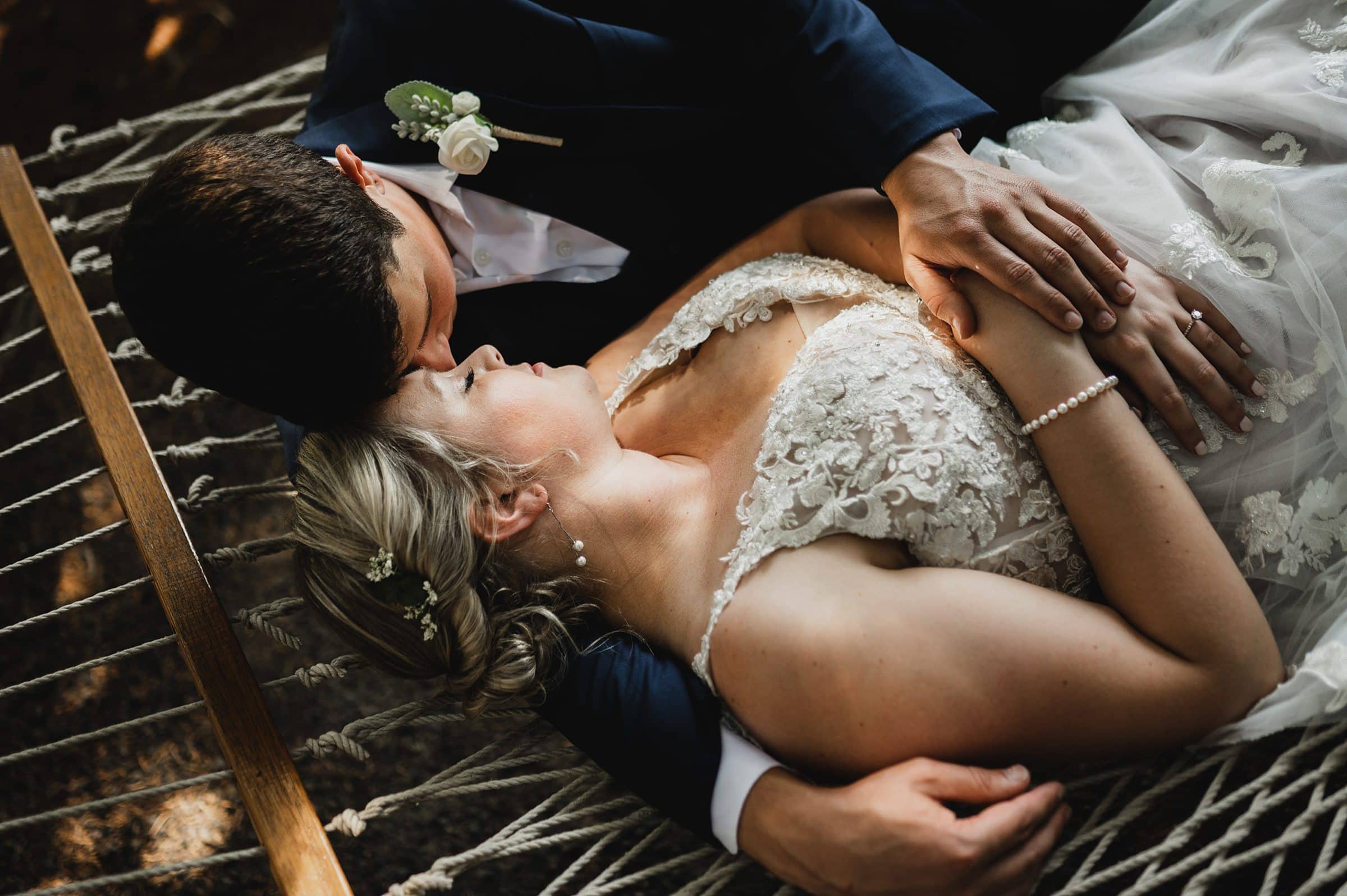 Bride and groom lie on a hammock at Gorge Crest Vineyards, embracing tenderly with peaceful expressions as they pose for their wedding photos.
