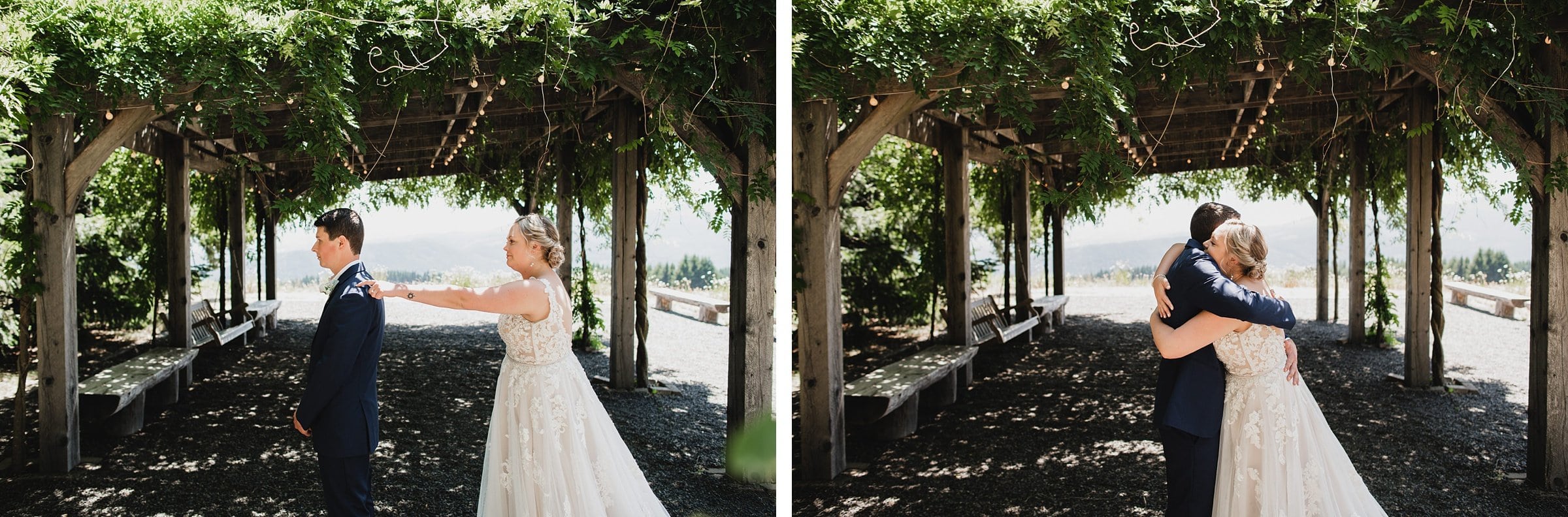 A bride taps the grooms shoulder as they stand under a vine-covered pergola, embracing while capturing wedding photos at Gorge Crest Vineyards on a sunny day.