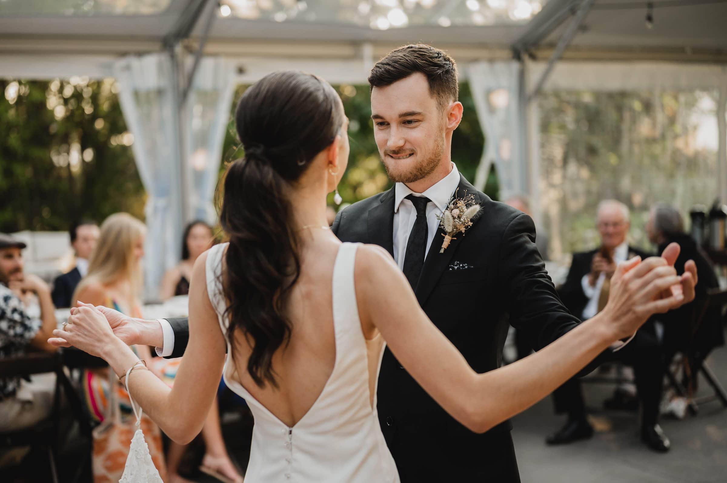 A couple dances together at a wedding photo session at The Griffin House, with the bride in a white dress and the groom in a black suit, surrounded by guests.