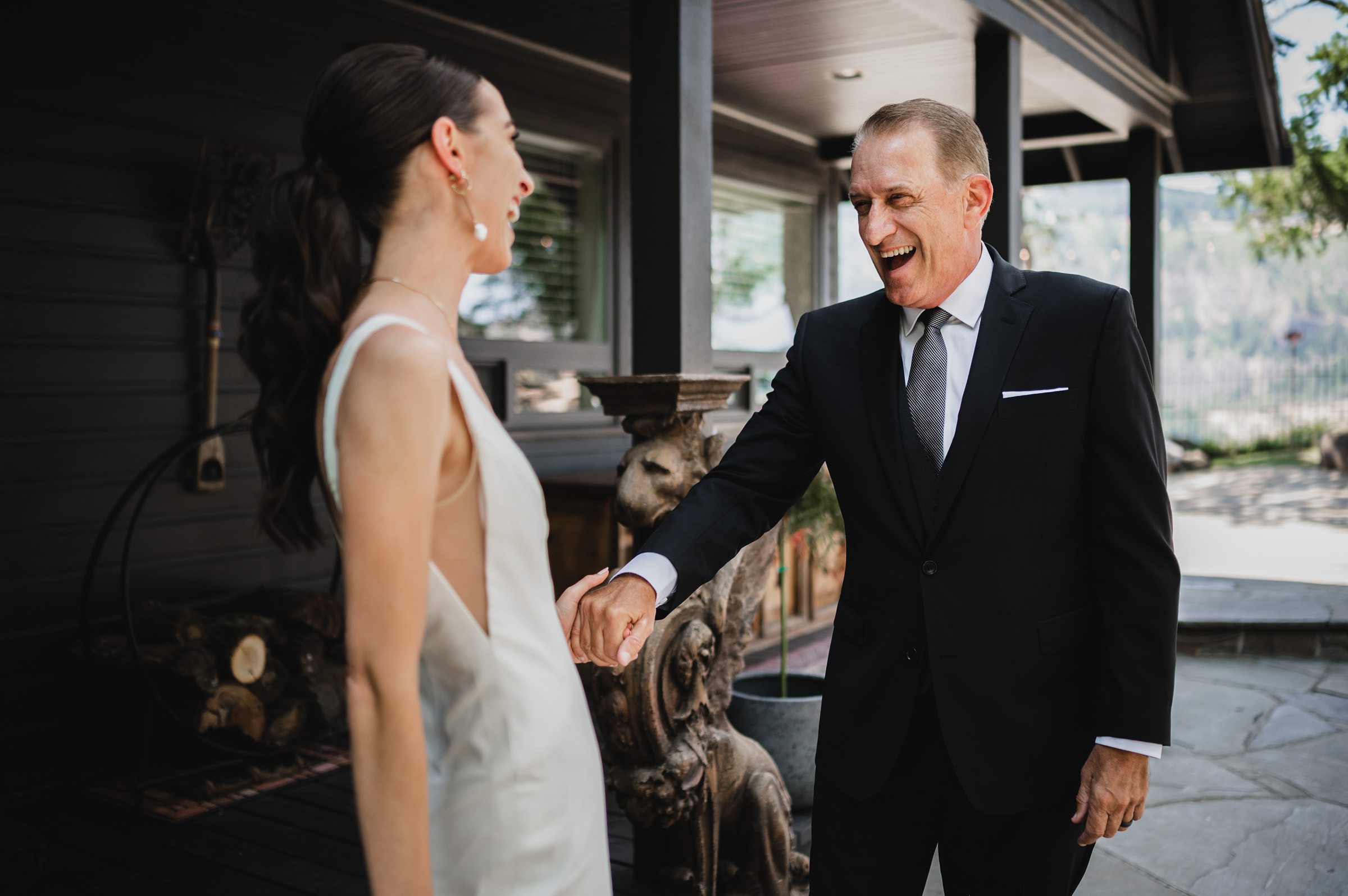 A bride in a white dress shares a joyful moment with a man in a suit outside The Griffin House, capturing perfect wedding photos.