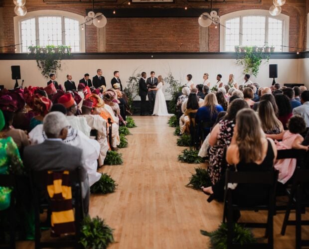 The Evergreen, a Portland Wedding Venue, hosts a beautiful ceremony with a couple at the altar and guests seated on both sides of the aisle in an elegantly decorated hall.