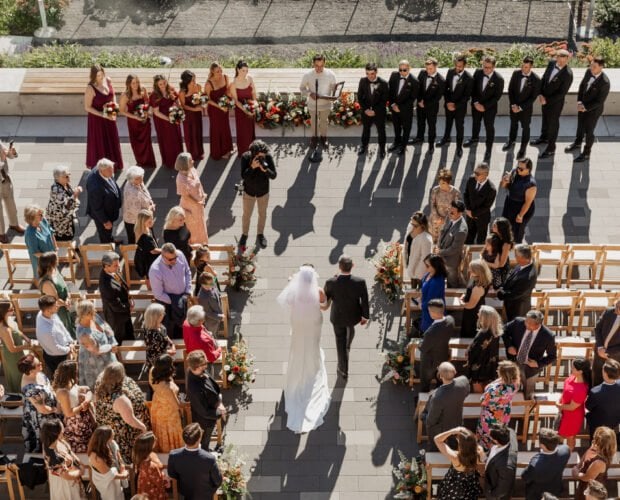 A bride walks down the aisle with her father at an outdoor wedding ceremony at Amaterra Winery, a stunning Portland wedding venue, surrounded by guests and the bridal party.