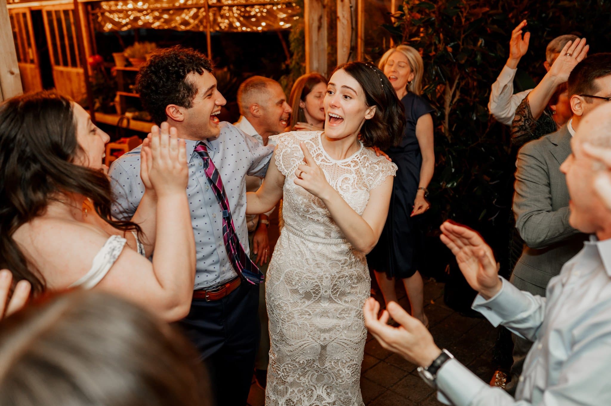 At Blockhouse, a vibrant Portland wedding venue, people dance joyfully indoors amid festive lights and lively expressions.