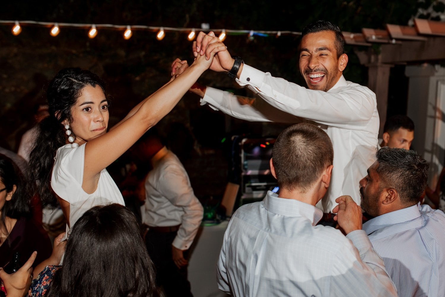 A couple dances together at an outdoor wedding party at Leach Botanical Garden, with guests in festive attire surrounding them.
