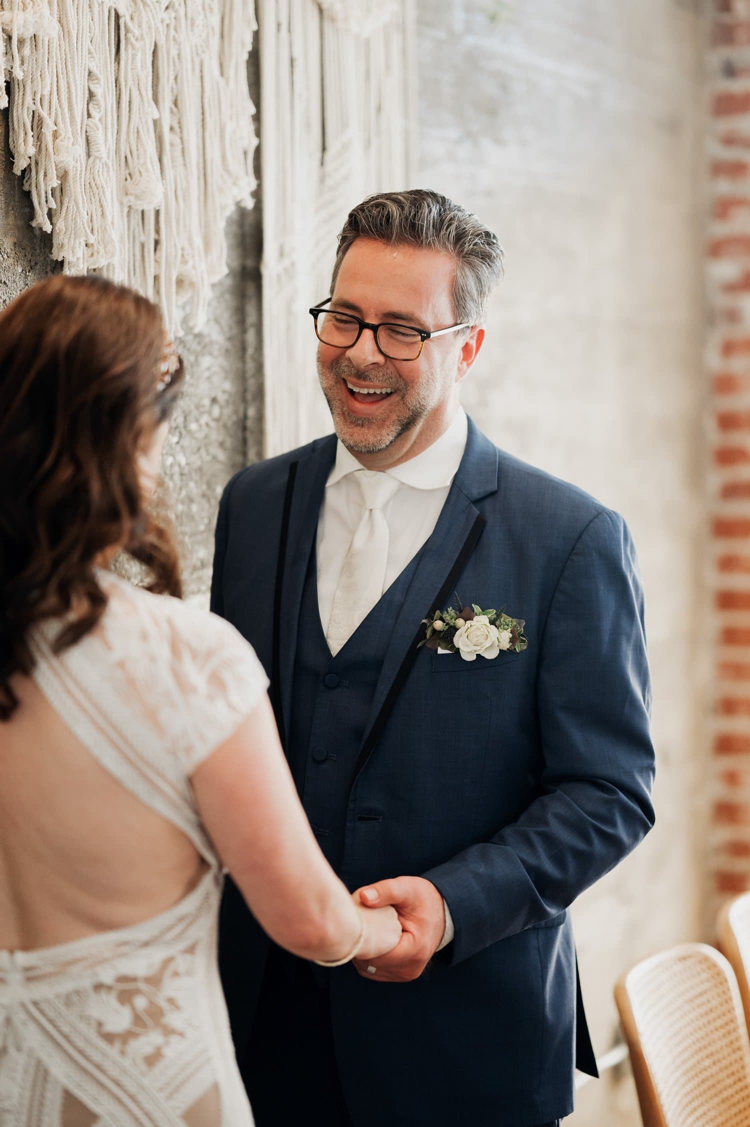 A couple holding hands and smiling at each other during their indoor wedding ceremony at Opal 28.