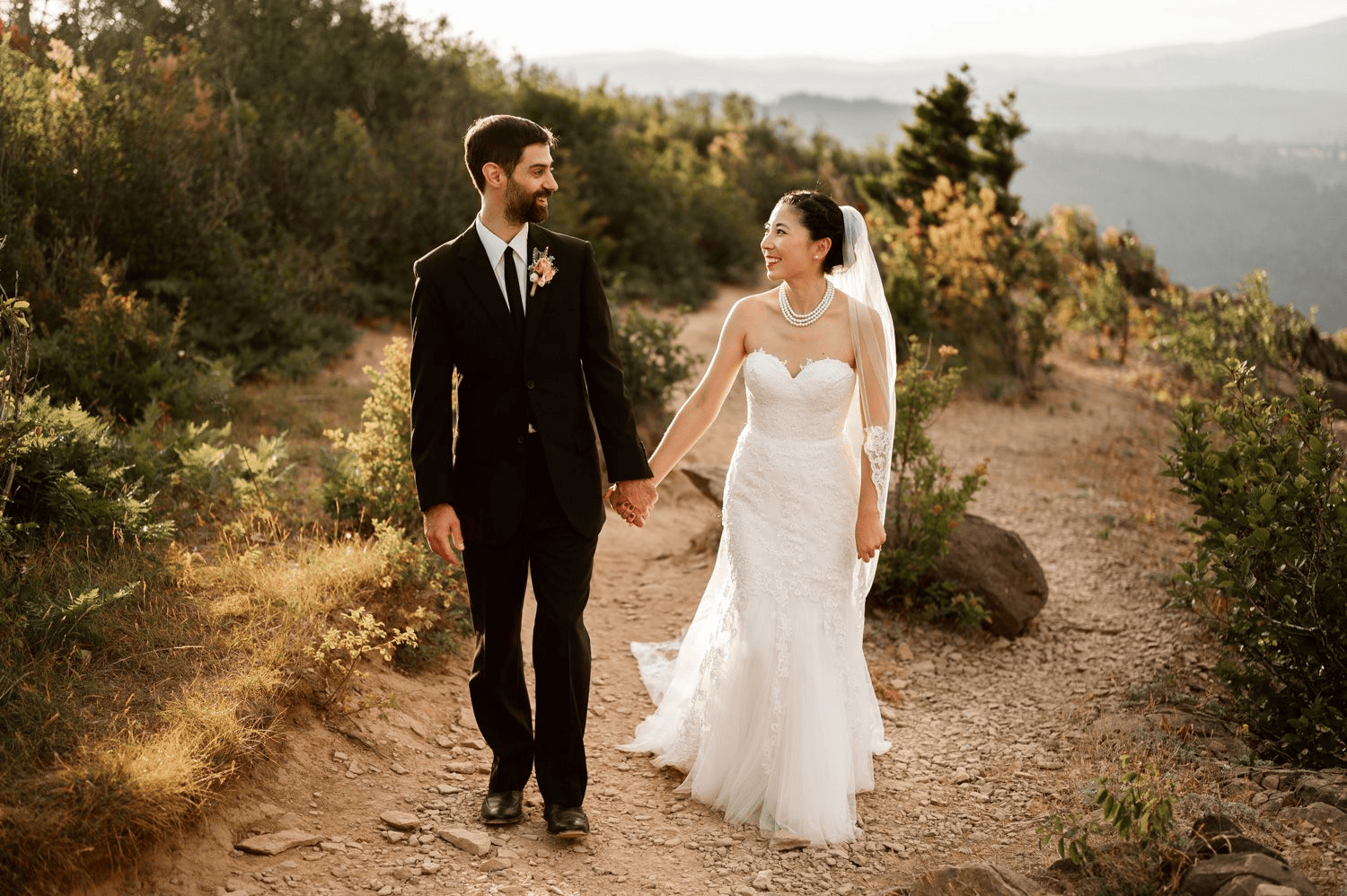 A bride and groom holding hands while walking along a dirt path on an elopement at Angels Rest in the Columbia River Gorge.