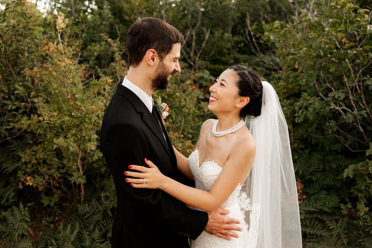 The bride and groom embrace joyfully outdoors, surrounded by vibrant greenery during their Angels Rest elopement.