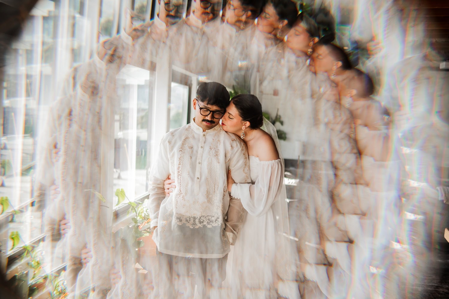 A couple in white formal wear embrace under natural light, with a kaleidoscope effect enhancing the scene at their wedding at Union/Pine.