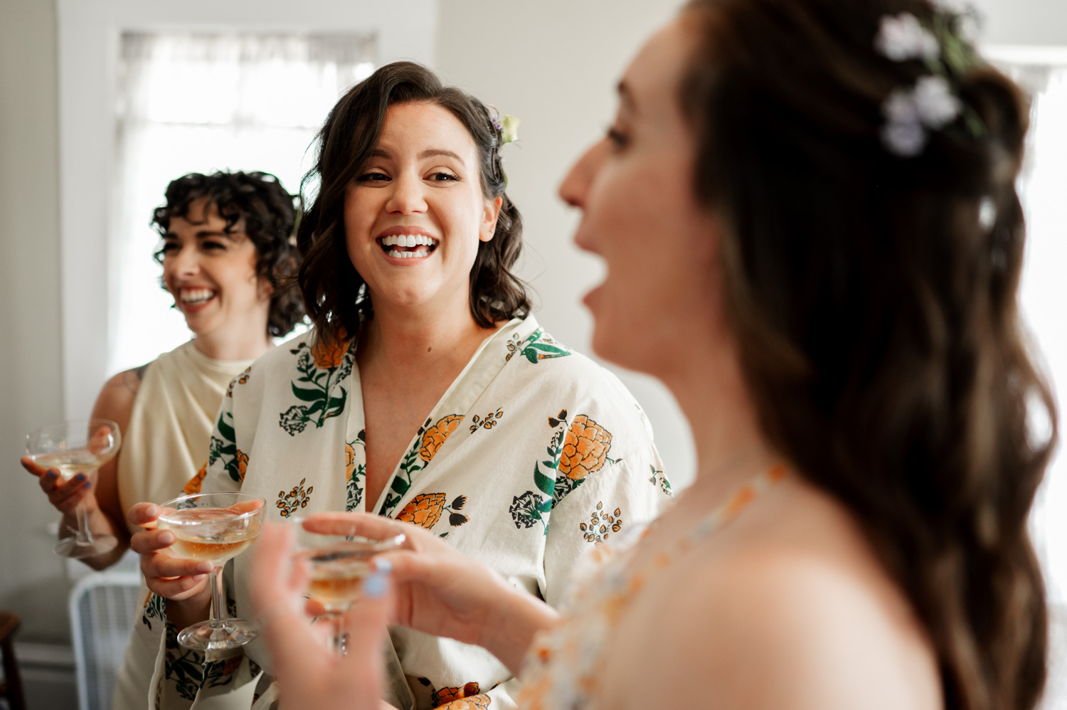 Three women smiling and raising their champagne glasses in celebration indoors.