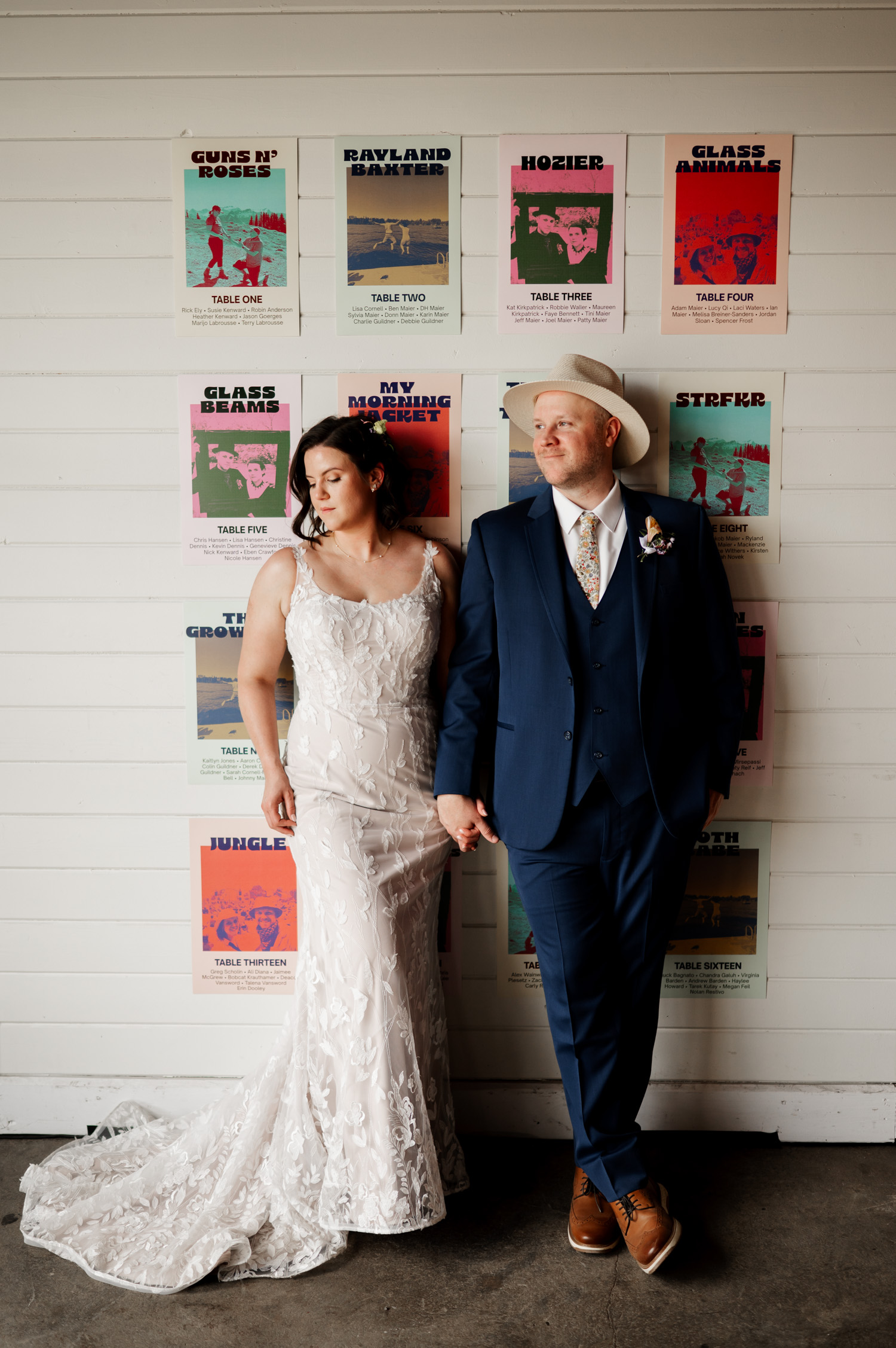 Bride and groom in formal wear stand against a wall with colorful posters at Rossi Farms, showcasing the vibrant atmosphere.