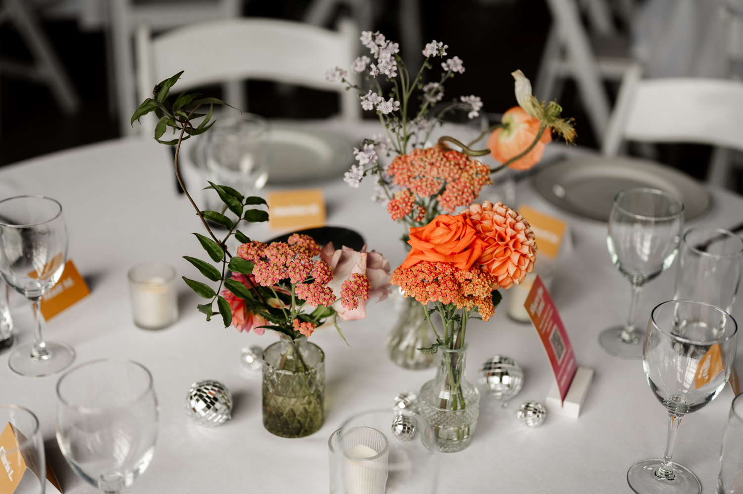 Table with floral centerpieces, glassware, and candles, showcasing the charm of Rossi Farms. Silver decorations add sophistication to the setup.