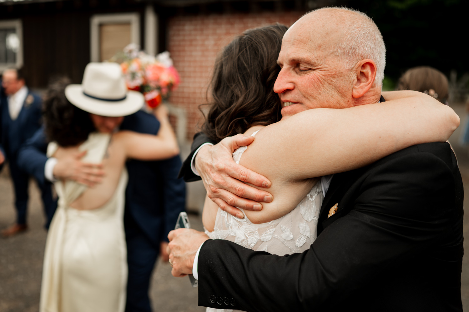 Two pairs of people embracing joyfully at an outdoor celebration, surrounded by a festive atmosphere, in a photo taken at Rossi Farms.