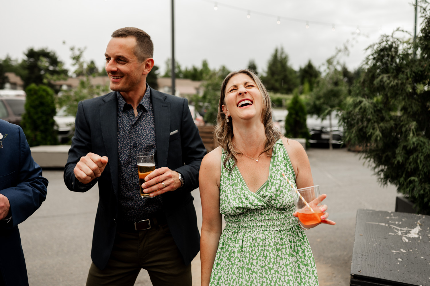 A man and woman laughing and dancing at Rossi Farms, holding drinks, surrounded by the picturesque setting captured in wedding photos.