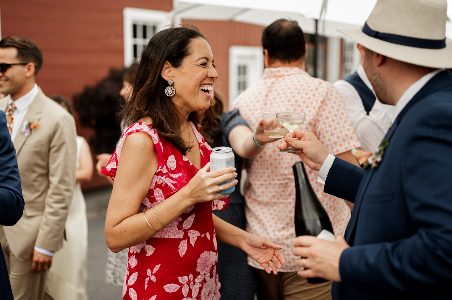 Guests at the Rossi Farms wedding smiling and chatting while holding drinks under a clear sky.
