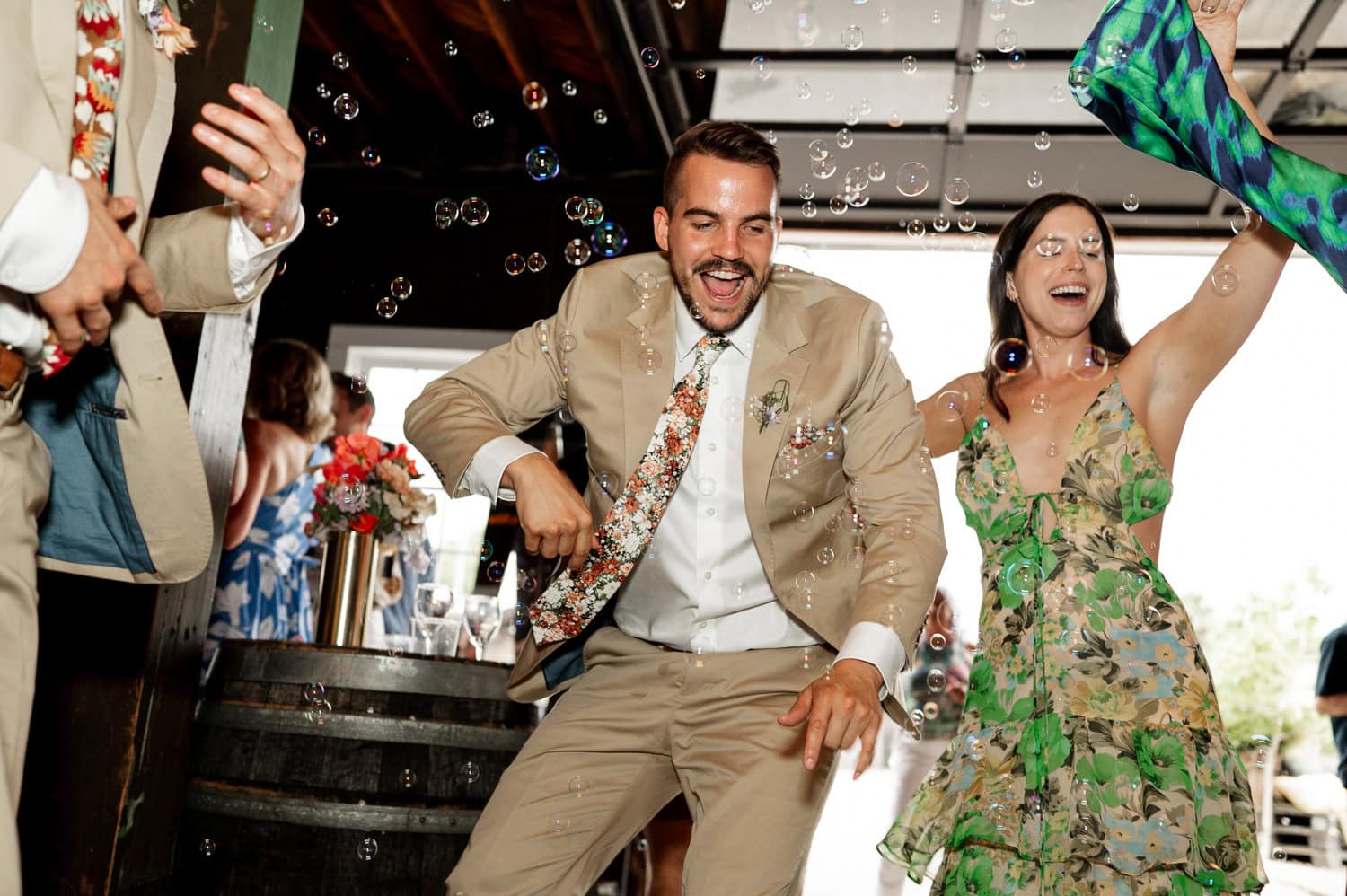 In a lively indoor setting, two people in festive attire joyfully dance among bubbles.