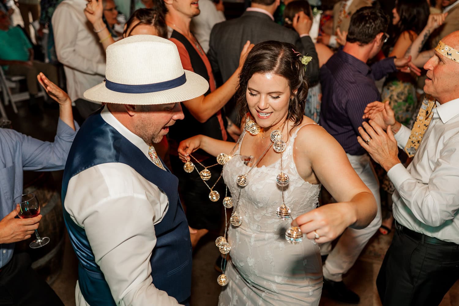At a lively Rossi Farms wedding reception, the bride and groom dance joyfully under twinkling string lights.