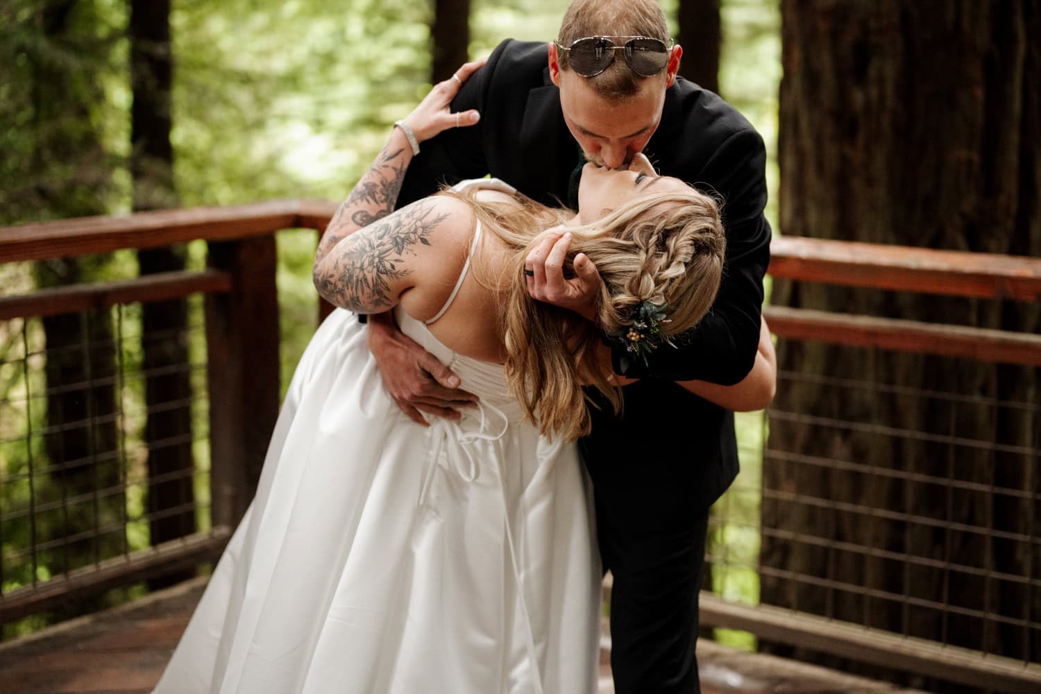 A bride and groom share a passionate first kiss during their elopement ceremony on Hoyt Arboretum's Redwood Deck surrounded by tall redwood trees.