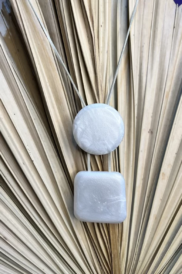 O fio de couro confere um toque natural e autêntico, enquanto o pingente em resina cintilante adiciona um brilho sutil e elegante.