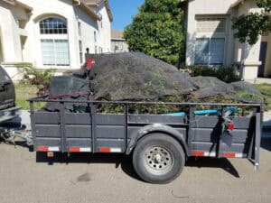 Rubbish and junk removal trailer loaded with debris in a residential area.