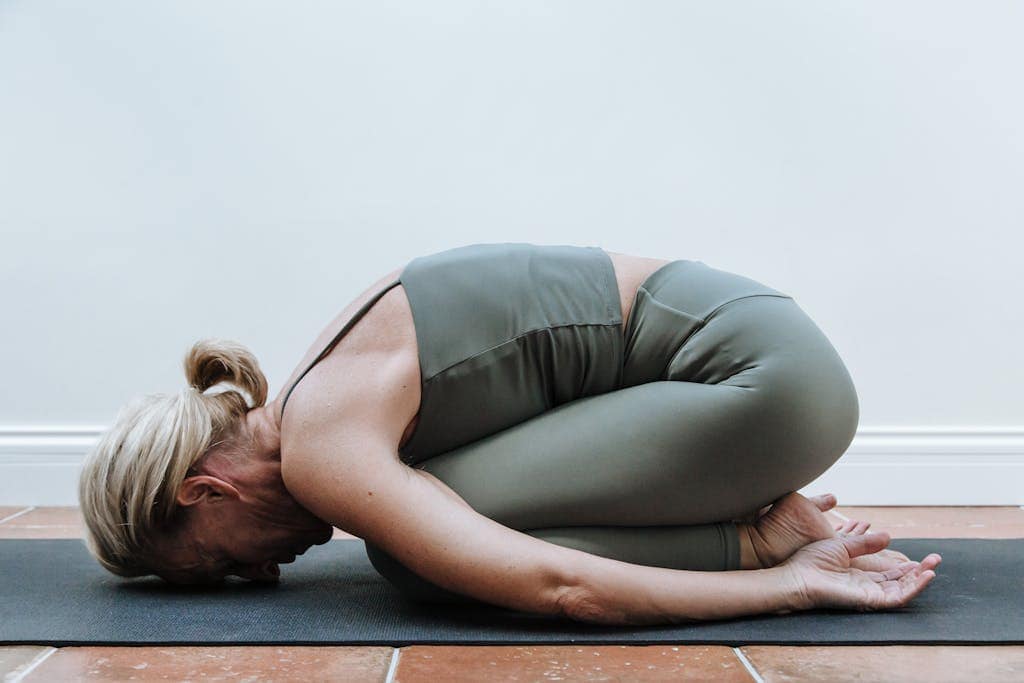 Adult woman performing yoga child's pose indoors, promoting relaxation and mindfulness.