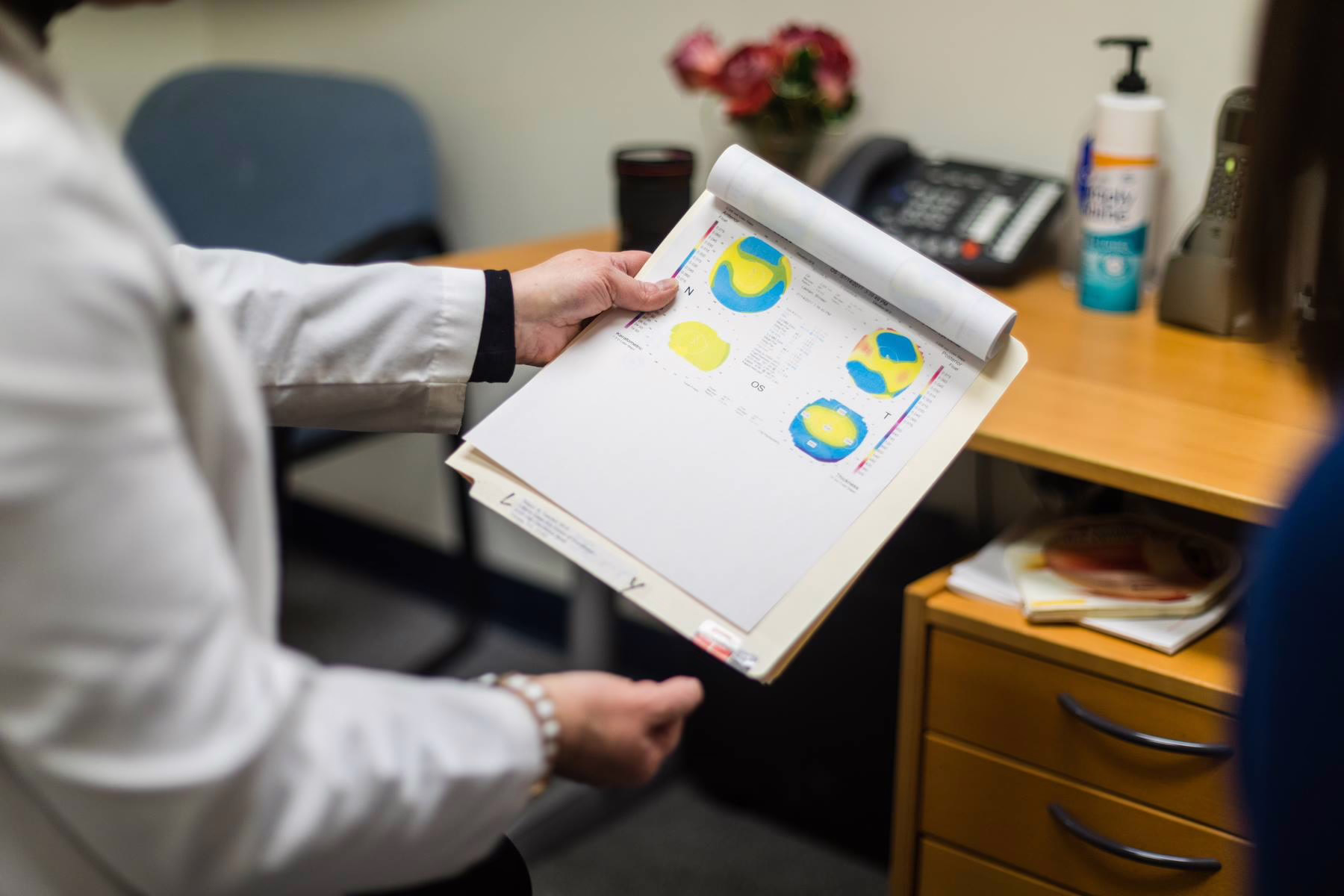 Person in white coat holding medical charts with colorful diagrams