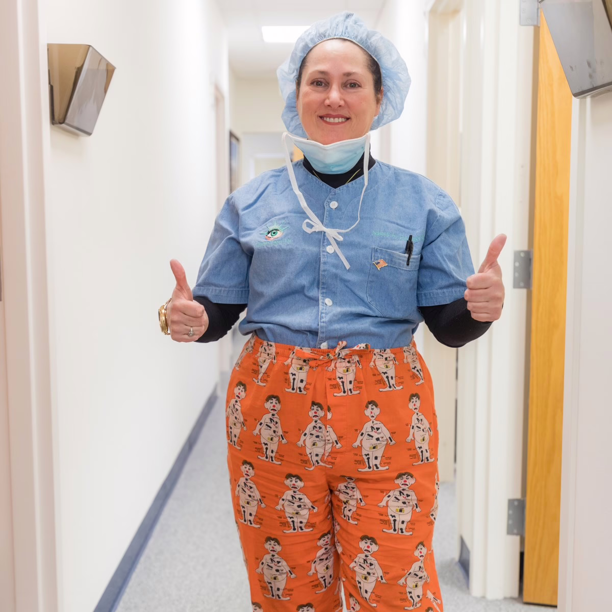 Smiling medical professional in scrubs and a surgical cap giving thumbs up