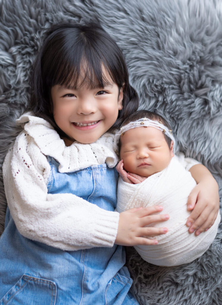 sibling sister take newborn baby for newborn photoshoot with Little One Photography