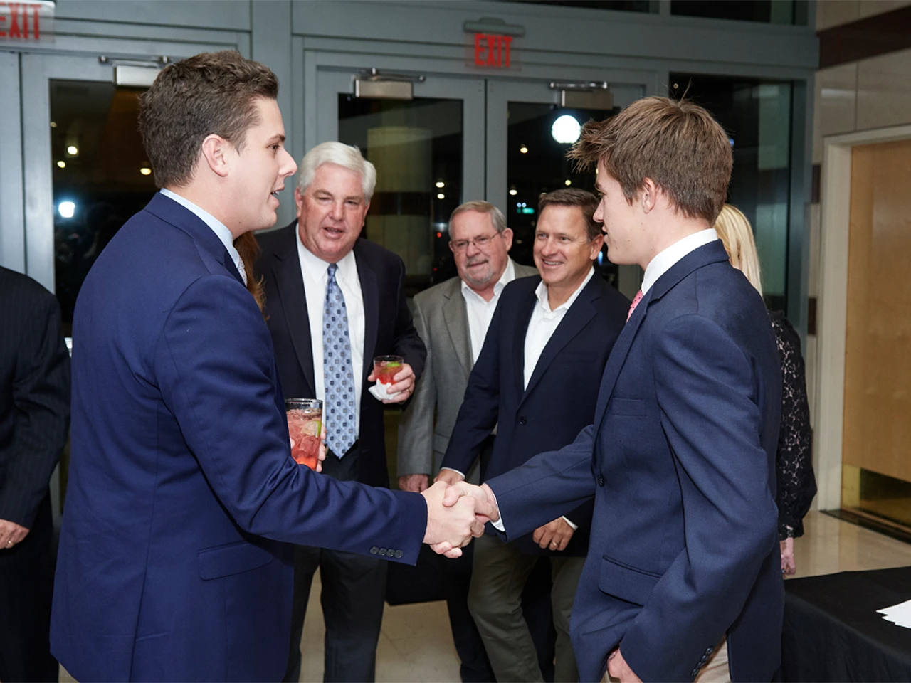 Two young men in suits shaking hands at the Lou Groza Award event.