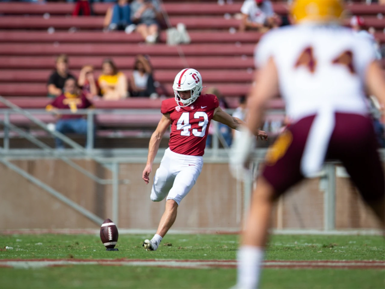 Football player in red jersey kicks ball during game at Lou Groza Award event.