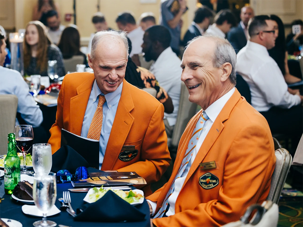 Two men in orange jackets smiling at a formal event, Lou Groza Award celebration.