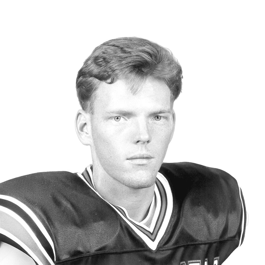 Black and white photo of a young football player in uniform with a serious expression.