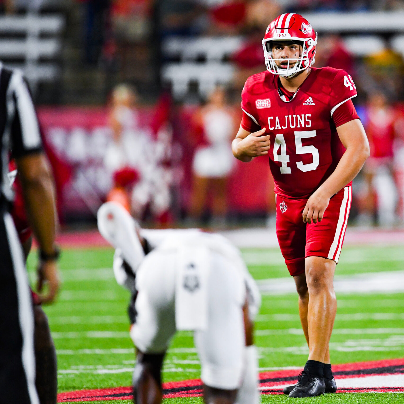 Football player in red Cajuns uniform on field during game.