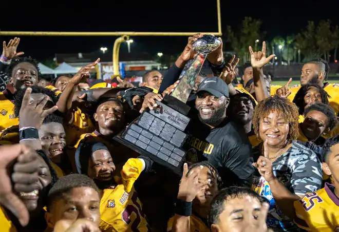 Football team celebrating with Lou Groza Award trophy after victory.