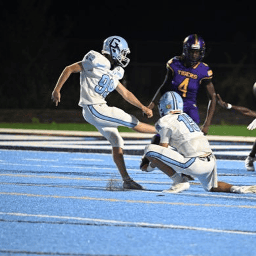 Football players in action during Lou Groza Award game on blue turf field.