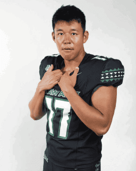 Football player wearing black jersey with number 17, posing confidently.