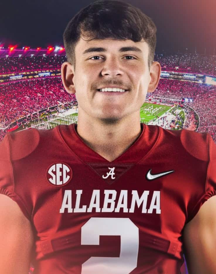 Alabama football player in red jersey at night game with stadium lights in background.