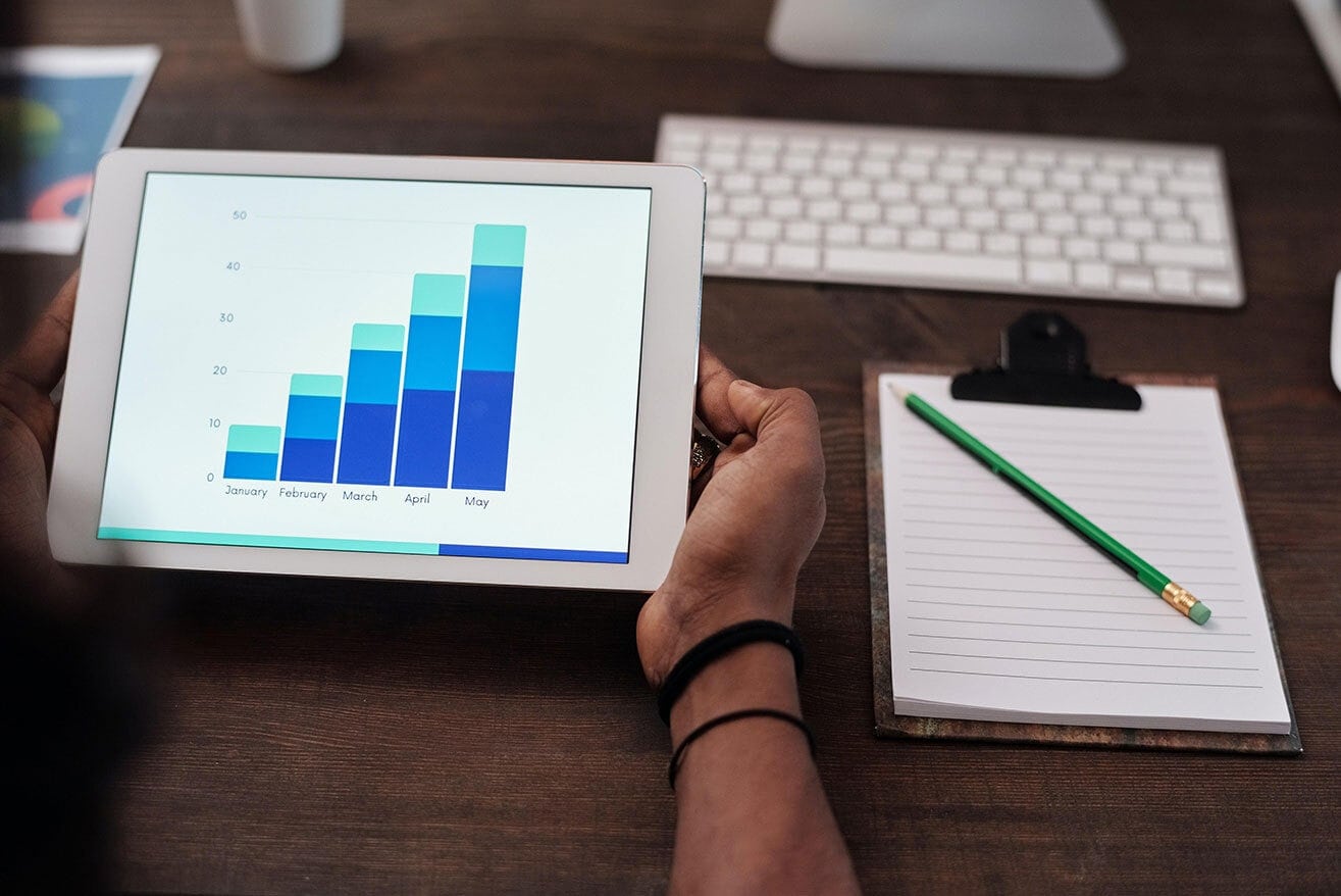 Person holding a tablet that shows bar charts by month