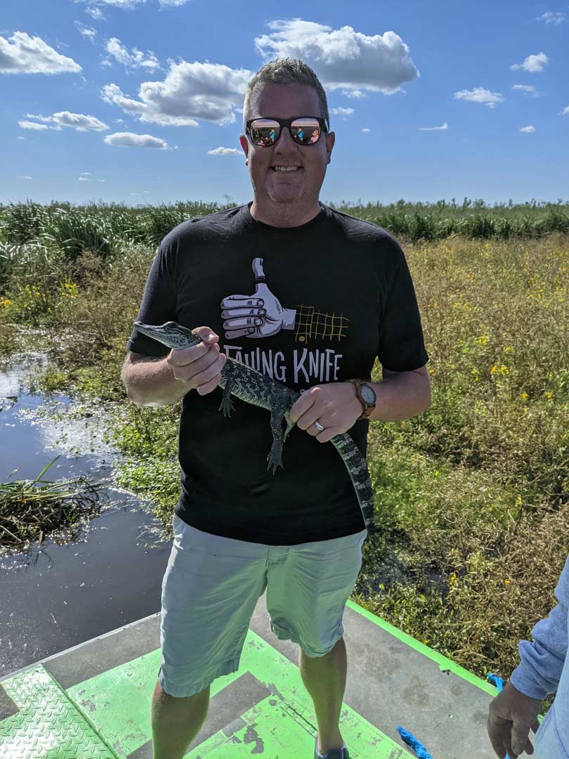 Robbie is outside in North LA holding a reptile.