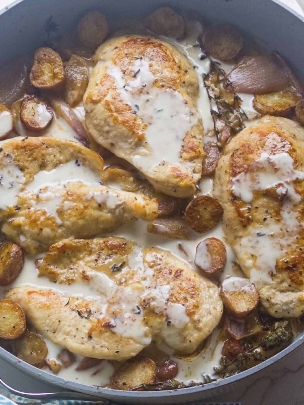 chicken with potatoes and shallots in a cider cream sauce in large skillet