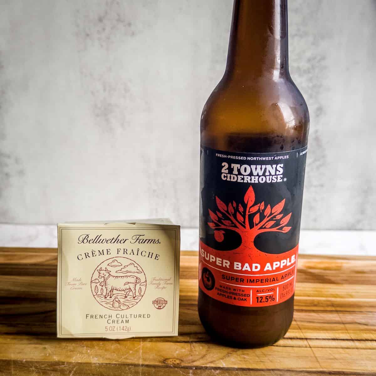 Carton of Bellwether Farms creme fraiche and bottle of 2 Towns Ciderhouse Super Bad Apple hard cider